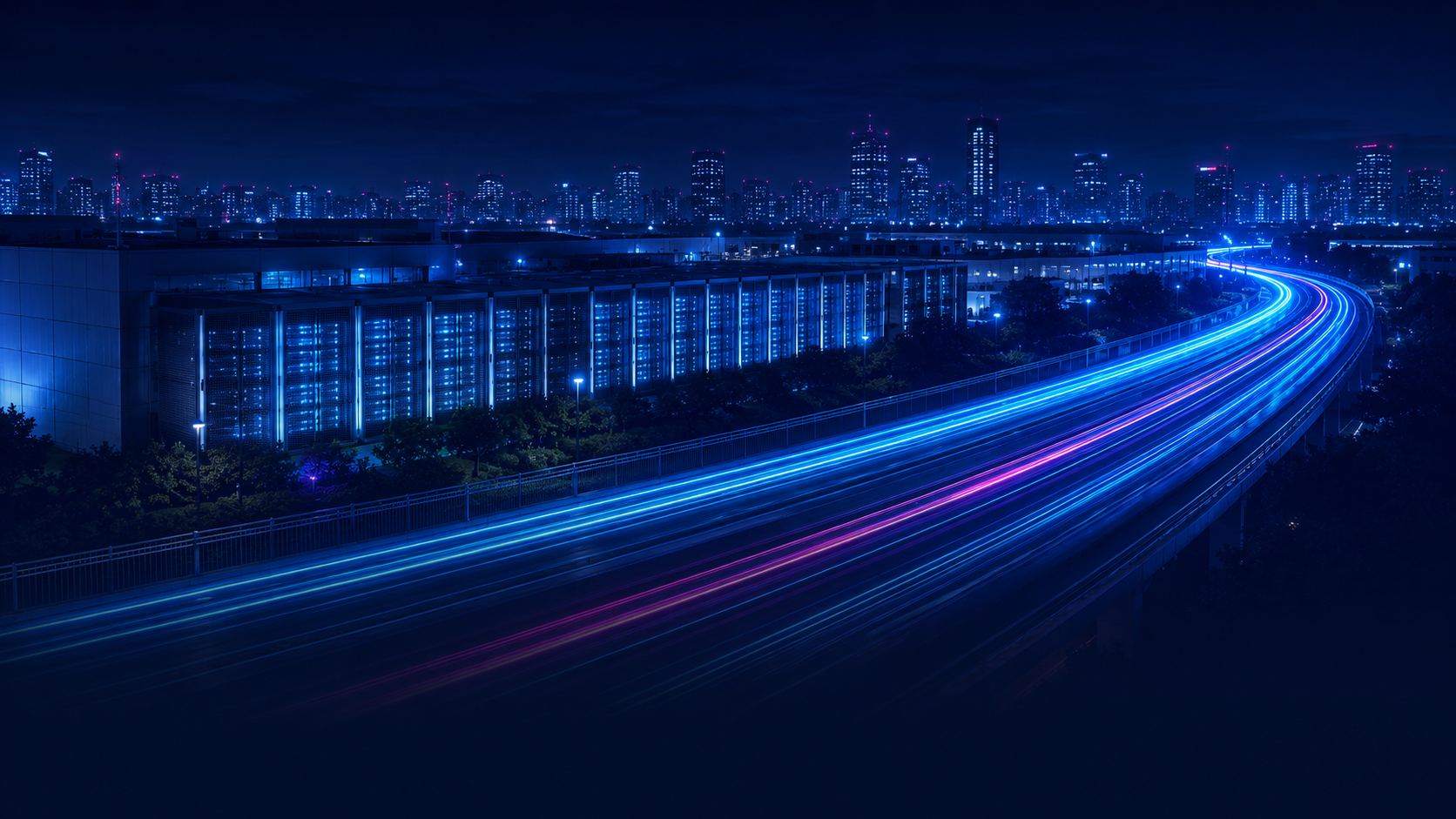 Data center beside a highway with light trails of high-speed traffic, with a city skyline at night